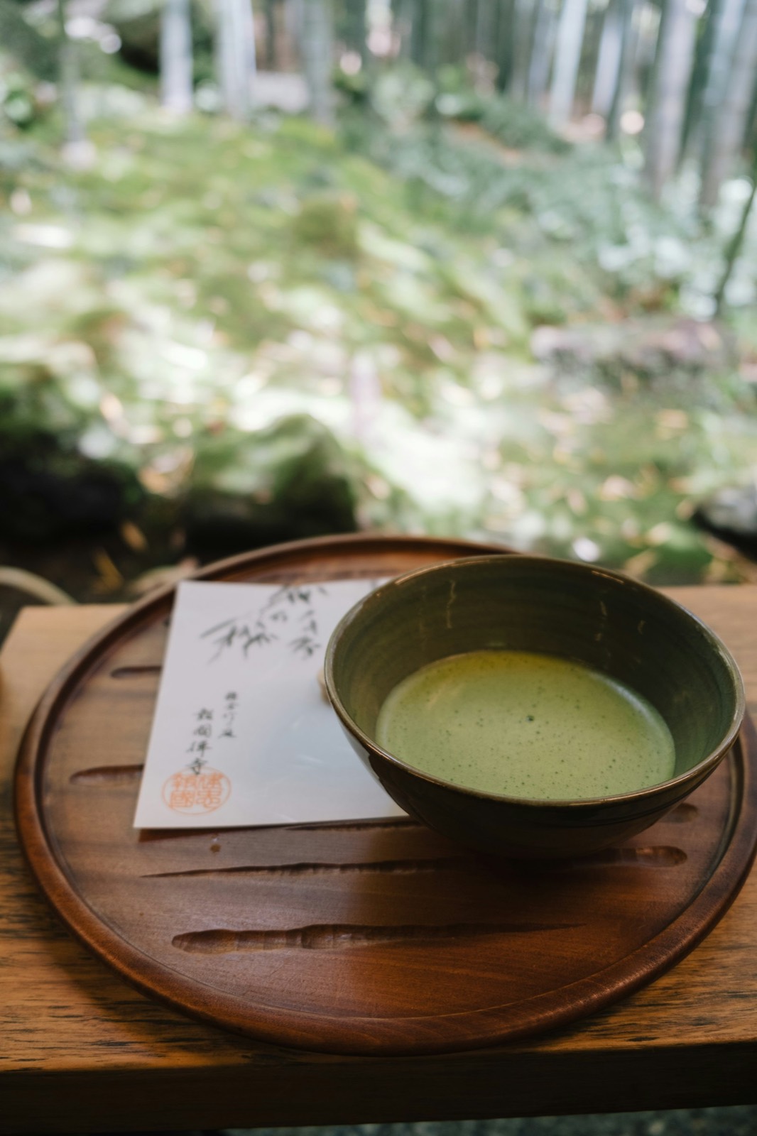 抹茶が点てられた茶碗と、竹林を望む静かな縁側