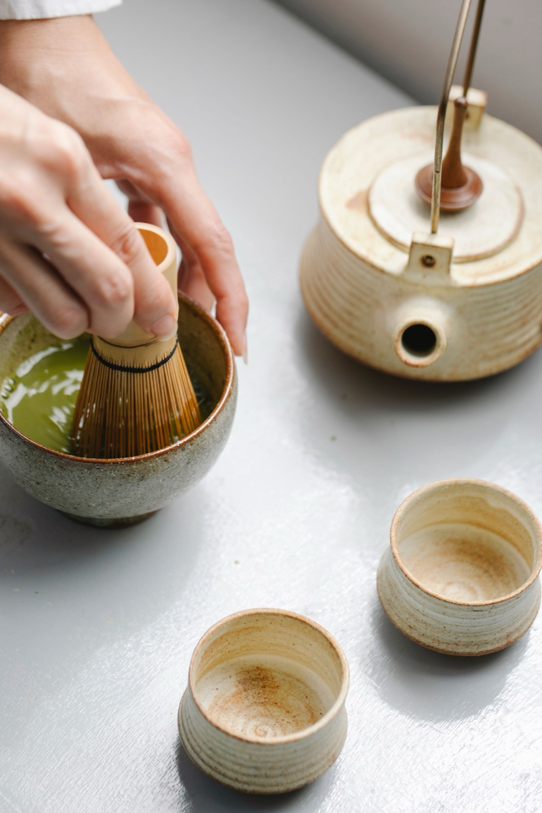 茶筅で抹茶を点てる手元と、湯冷ましの陶器